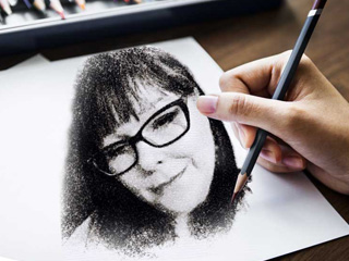Charcoal Drawing A hand with a pencil in it drawing and image of Soul To Soul Medium Eileen Casey. It is a picture of her head, she has glasses and long hair.