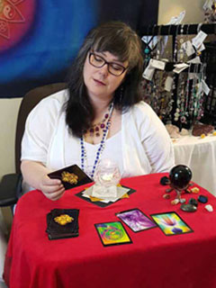 Eileen sitting at a table with a red cloth looking into oracle cards.